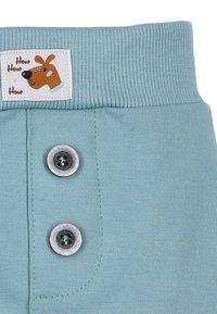 Jasnoniebieskie bawełniane szorty z ribbrowym pasem, z dwoma szarymi guzikami i metką z ilustracją psa oraz napisem "How How How."