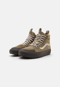 Kaki høyhælte sneakers i semsket lær og lerretsmateriale, hvite snorer, gummitåhette og teksturert såle med et grønt akcenttag.
