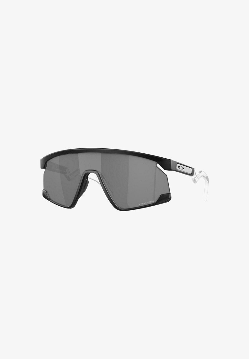 Occhiali da sole neri con design avvolgente, lenti grigie e tempiali in silicone trasparente. Presentano una struttura slim e sportiva con dettagli laterali.