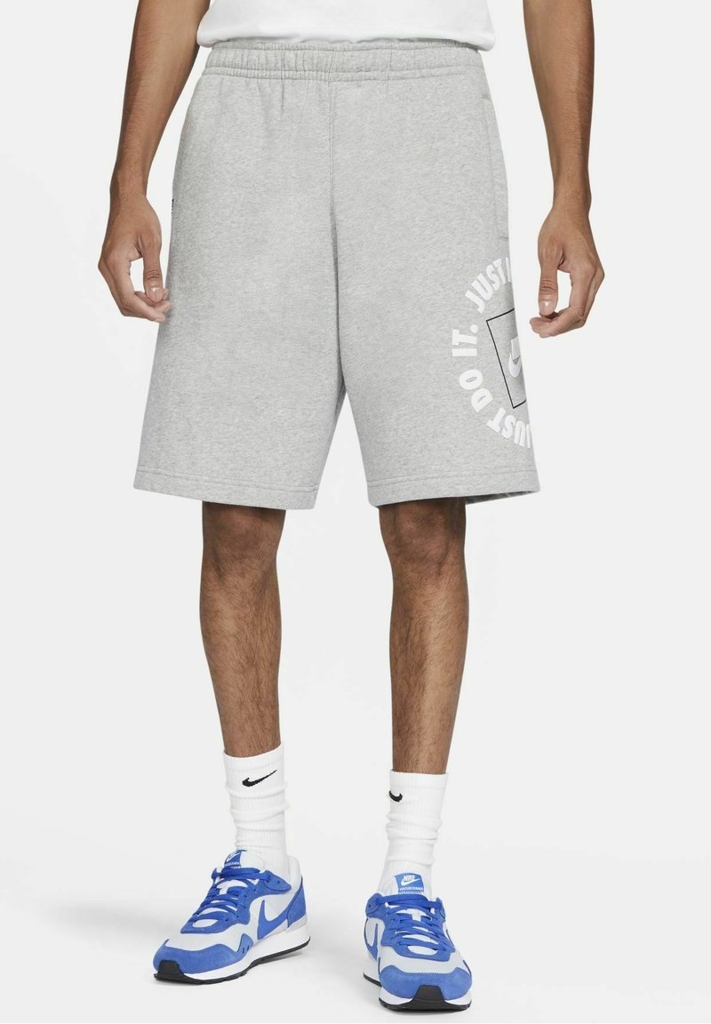 Pantalones cortos de algodón gris con mezcla, con cintura elástica y bolsillos laterales; presenta el texto y el logo en blanco "JUST DO IT" impresos en la pierna izquierda.