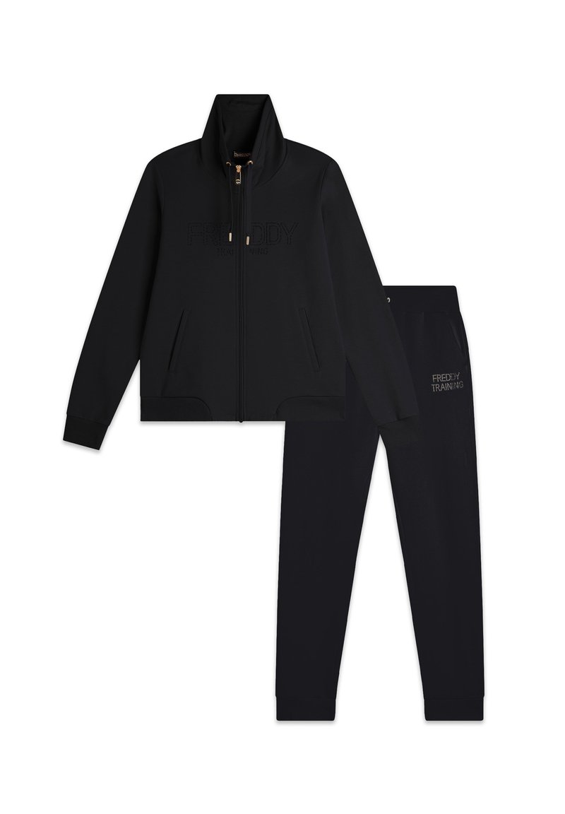 Completo tuta nera composto da una giacca con zip e logo in rilievo e pantaloni abbinati, entrambi dotati di polsini a costine e tasche laterali.