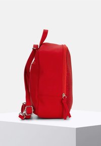 Borsa a spalla in pelle vegana rossa con forma arrotondata, motivi decorativi intagliati, chiusura con zip e tracolla regolabile.