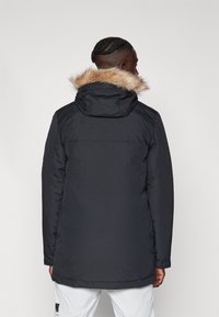 Μαύρο επενδυμένο μπουφάν με επένδυση από ψεύτικη γούνα στην κουκούλα, με ίσια γραμμή και μακριά μανίκια, ορατές λεπτομέρειες ραφής στην πλάτη.