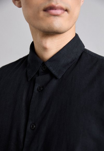 Čierna košeľa na gombíky so štruktúrovaným golierom, s hladkou textúrou a piatimi čiernymi gombíkmi pozdĺž prednej časti.
