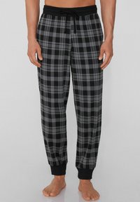 Zwarte en grijze geruite pyjamabroek met een elastische tailleband, trekkoord en elastische boorden bij de enkels. Zacht stoftextuur.