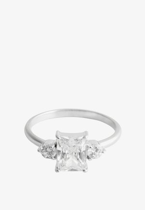 Silver ring with a large rectangular-cut clear gemstone in the center and smaller round clear gemstones on each side against a white background.