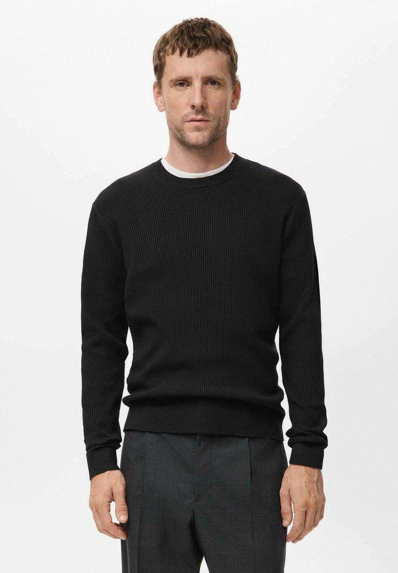 Suéter negro de canalé con cuello redondo y mangas largas, que presenta una tela texturizada y puños ajustados, combinado con pantalones grises.