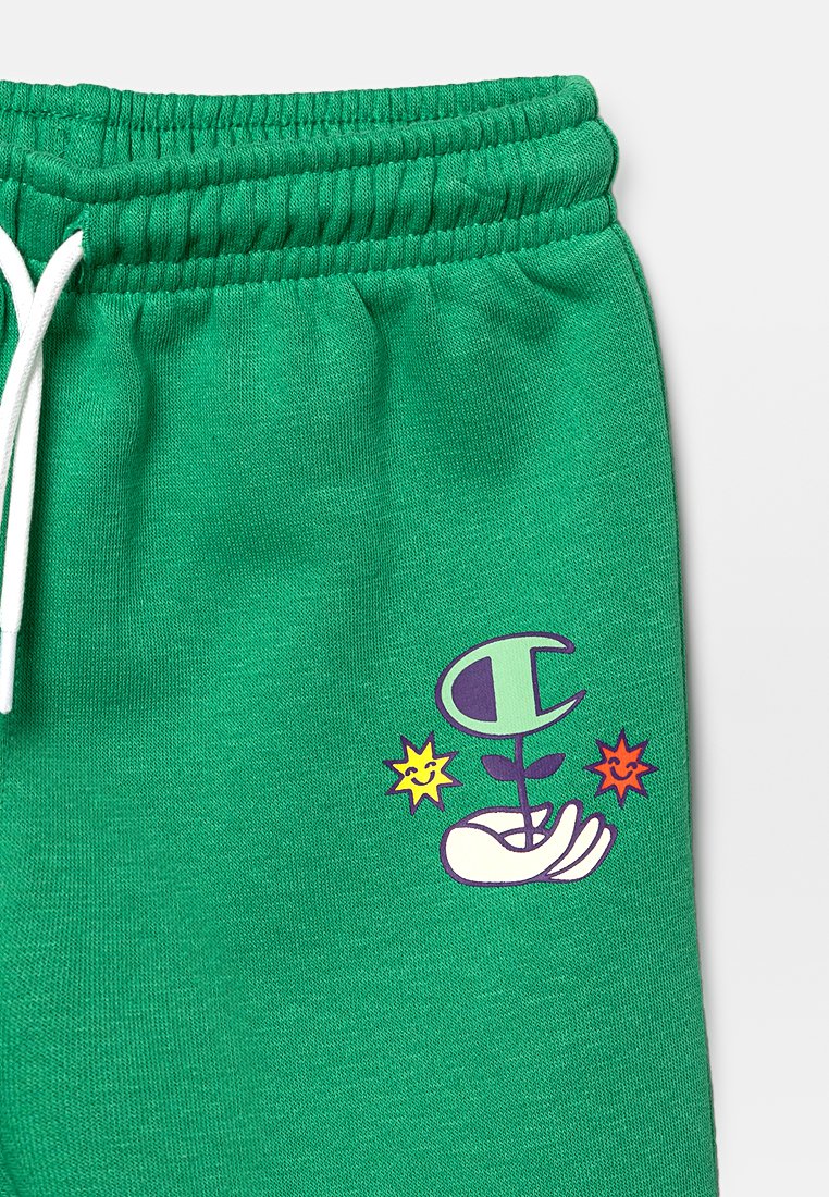 Pantaloni della tuta verdi realizzati in morbido tessuto, con una cintura elastica e una grafica stampata di una mano che tiene una pianta con dettagli colorati.