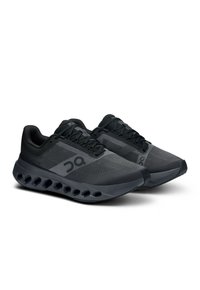 Chaussures de sport noires avec une tige en mesh, surface texturée et semelle rembourrée avec des poches d'air visibles. Marquage sur le côté.