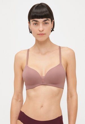 Soutien-gorge rembourré couleur brun clair avec des bretelles ajustables fines, texture lisse, design de bonnets incurvés et un panneau en tissu central à l'avant.