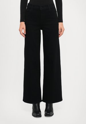 Wide-leg black jeans made from denim, featuring front pockets, a button closure, and a polished finish. Worn with black ankle boots.