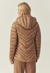Veste matelassée isolante marron avec un motif chevron, capuche et manches longues, dotée d'une texture extérieure lisse et brillante.