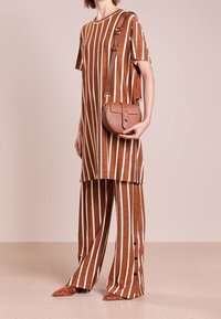 Braun-weiße gestreifte übergroße Tunika, kombiniert mit passenden weiten Hosen; beinhaltet eine Umhängetasche und strukturierter Stoff.