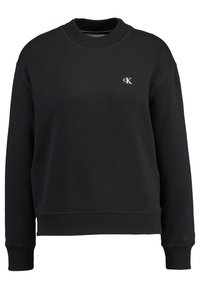 Sudadera negra con cuello redondo, puños y dobladillo acanalados, que presenta un logo blanco de "CK" en el pecho. La tela tiene una textura suave y lisa.