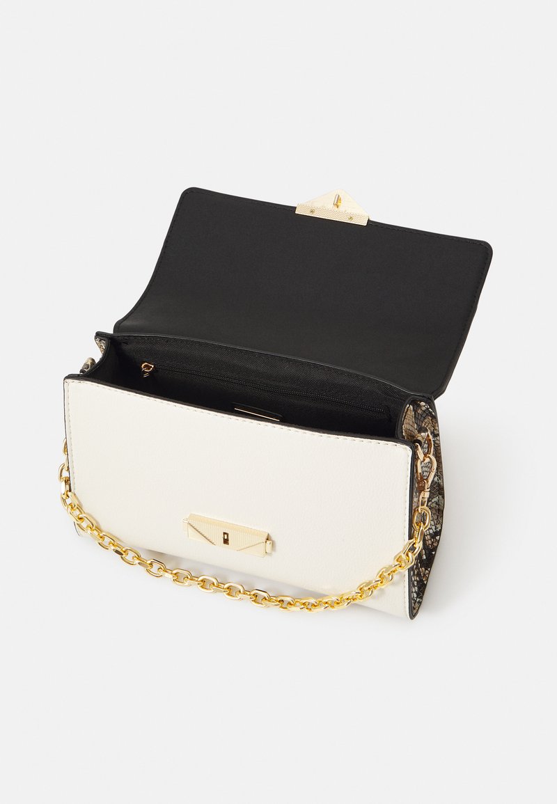 Sac à main en cuir blanc avec une bandoulière en chaîne dorée, doté d'un intérieur noir et d'un fermoir texture en or. Détail motif le long des bords.