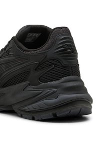 Bageste udsigt af sort atletisk sneakers med mesh og syntetiske overlays, polstret sål og Puma-logo på hælblokken.