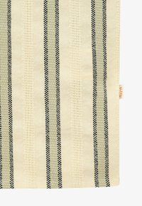 Tissu crème avec des rayures tissées verticales noires et grises alternant avec des rayures crème texturées, présentant une petite étiquette de marque sur le bord droit.