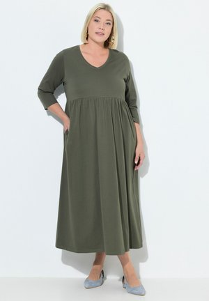 Olivegrünes, knielanges Kleid mit V-Ausschnitt und Dreiviertelärmeln. Es hat ein enges Oberteil und einen fließenden Rock mit seitlichen Taschen.