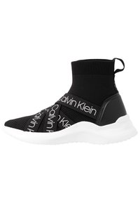 Černé pletené tenisky s vysokým kotníkem, zdobené bílým logem Calvin Klein na elastických páscích a bílou gumovou podrážkou. Texturovaný svršek, elegantní design.