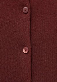 Bordeauxfarbene Strickjacke mit zwei runden Knöpfen. Weicher Stoff mit Nahaufnahme der Gewebestruktur und Knopfdetails. Einfaches Design.
