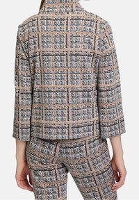 Skräddarsytt blazer- och byxset, mönstrat med svart, vitt och orange rutmönster. Strukturerad tyg med trekvartsärmar.