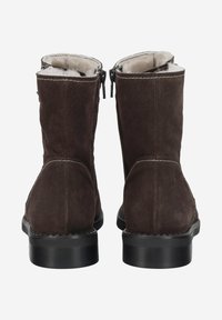 Bottines en daim marron à la texture lisse, fermées par une fermeture éclair, avec un petit talon noir. Doublure intérieure en fourrure. Détails de coutures visibles.