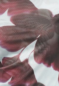 Κόκκινα και σκούρα μωβ αφηρημένα λουλουδένια μοτίβα σε λευκό υφασμάτινο φόντο με ορατό λεπτό πλέγμα υφής.