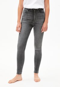 Jeans gris de corte slim-fitting y cintura alta, hechos de denim. Presentan cinco bolsillos, un cierre de cremallera y una textura suave.