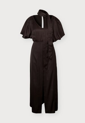 Femme portant une longue robe marron foncé à manches courtes, col en V, fente à l'avant, foulard assorti autour du cou et chaussures à talons ouvertes noires.