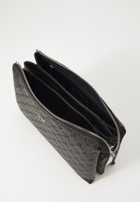 Fekete bőr táska texturált külsővel, zipzár nélkül, három rekesszel és elegáns belső dizájnnal.