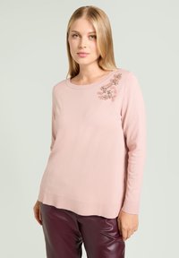Maglione a maglia rosa chiaro con scollo rotondo e maniche lunghe, decorato con applicazioni floreali sulla spalla sinistra. Texture liscia.