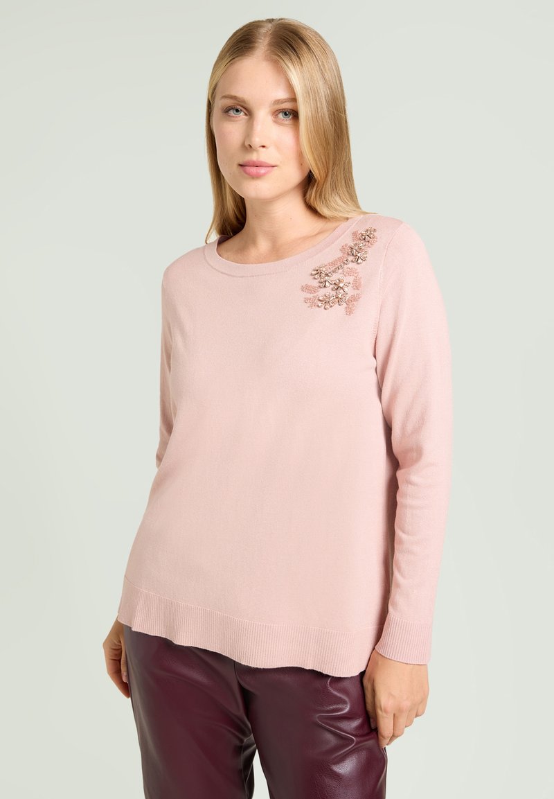Maglione a maglia rosa chiaro con scollo rotondo e maniche lunghe, decorato con applicazioni floreali sulla spalla sinistra. Texture liscia.