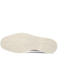 Weiße Gummisohle mit strukturierten Mustern, geschwungenem Design und eingeprägtem Branding. Flache, runde Form für Komfort und Grip.
