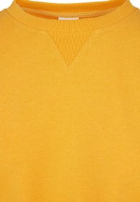 Sudadera amarilla con cuello redondo acanalado y un detalle en forma de V en el centro. Fabricada con un tejido suave y texturizado.