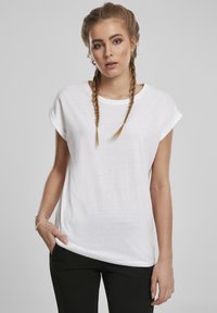 Valge, lühikeste varrukatega t-särk, mille lõige on lõdvestunud ja kaelus on ümmargune. Valmistatud pehmest kangast, õigete varrukaäärtega ja ilma nähtavate mustriteta.