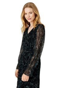 Dark green velvet dress with sheer long sleeves, V-neck, and subtle marble patterns. Fitted waist with pleated detailing. Smooth texture.