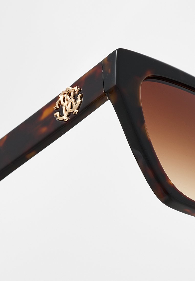 Lunettes de soleil en écaille de tortue avec des montures angulaires, des verres dégradés marron et un détail logo doré sur la branche.