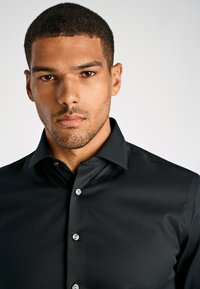 Zwarte, lang mouwen shirt met een button-down kraag, gladde textuur en zilveren knopen aan de voorkant, met een getailleerde pasvorm.