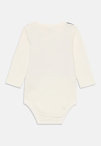 Cremfarbener Baby-Body mit langen Ärmeln und Druckknöpfen am Boden, von hinten auf einem schlichten weißen Hintergrund gezeigt.