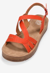 Sandalias naranjas de cuña con tiras trenzadas, plantilla acolchada de color marrón y suela gruesa de color marrón. Incluye una correa ajustable para el tobillo y detalles de costura.