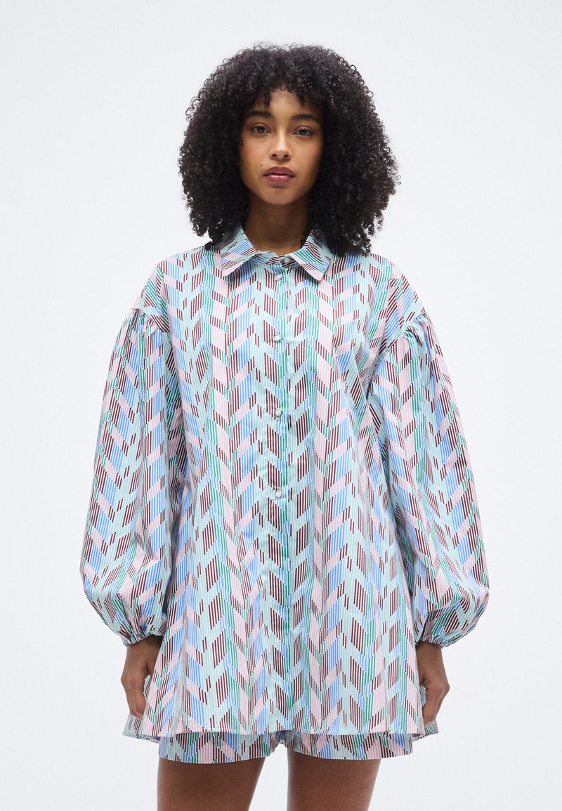 Εκτυπωμένο πουκάμισο σε υπερμεγέθη γραμμή με γιακά, διαθέτει έντονα γεωμετρικά σχέδια σε παστέλ αποχρώσεις και φουσκωτά μανίκια.