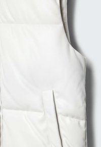 Hvid lædervest med en glat tekstur, der har syningsdetaljer og en sidelomme. Designet er minimalistisk med rene linjer.