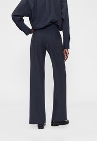 Wijde broekspijpen in donkergrijze stof met een gladde textuur. Voorzien van achterzakken en een gestructureerde tailleband voor een getailleerde pasvorm.