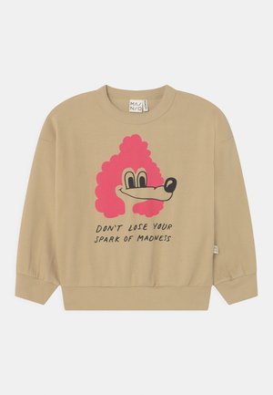 Sweat-shirt beige à col rond, à manches longues et avec des poignets côtelés. Présente un visage de chien en cartoon rose et un texte noir : "NE PERDS PAS TA FOLIE."