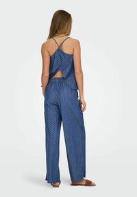 Niebieski, dwuczęściowy zestaw składający się z bezrękawowej bluzki z wycięciem na plecach oraz luźnych, wzorzystych spodni z szerokimi nogawkami. Miękka, lekka tkanina.