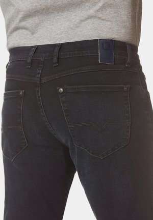 Dunkelblaue Denim-Jeans mit einem taillierten Design, ausgestattet mit Gesäßtaschen, die ein Chevron-Stichmuster aufweisen, und einem blauen Lederlogo-Patch am Bund.