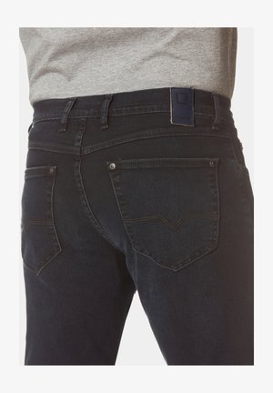 Dunkelblaue Denim-Jeans mit einem taillierten Design, ausgestattet mit Gesäßtaschen, die ein Chevron-Stichmuster aufweisen, und einem blauen Lederlogo-Patch am Bund.