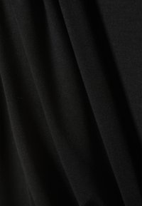 Close-up of black fabric with visible texture and gentle folds creating soft shadows.