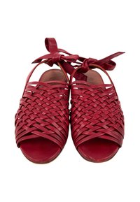 Paire de sandales en cuir rouge avec brides tressées et attaches à la cheville, design à bout ouvert, vues de face sur fond blanc.