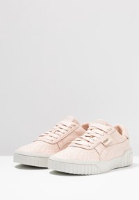 Baskets rose clair avec dessus en cuir texturé, embout perforé, lacets plats et semelle en caoutchouc blanc texturée. Logo PUMA sur le côté.